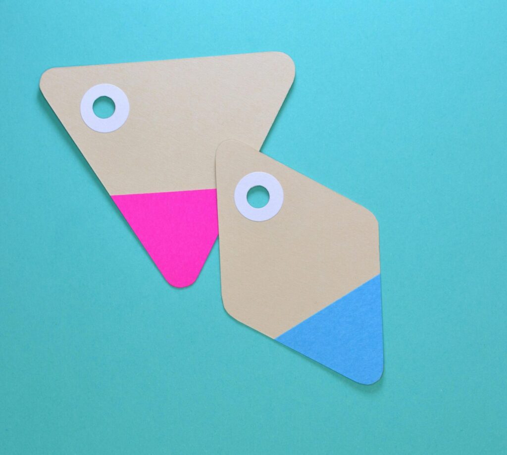Two colorful paper tags with holes on a teal background. Ideal for design and marketing concepts.
